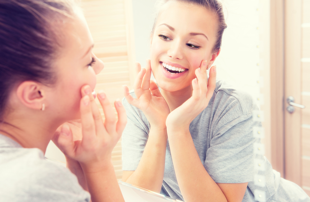 Young Woman Looking at Her Skin in a Mirror